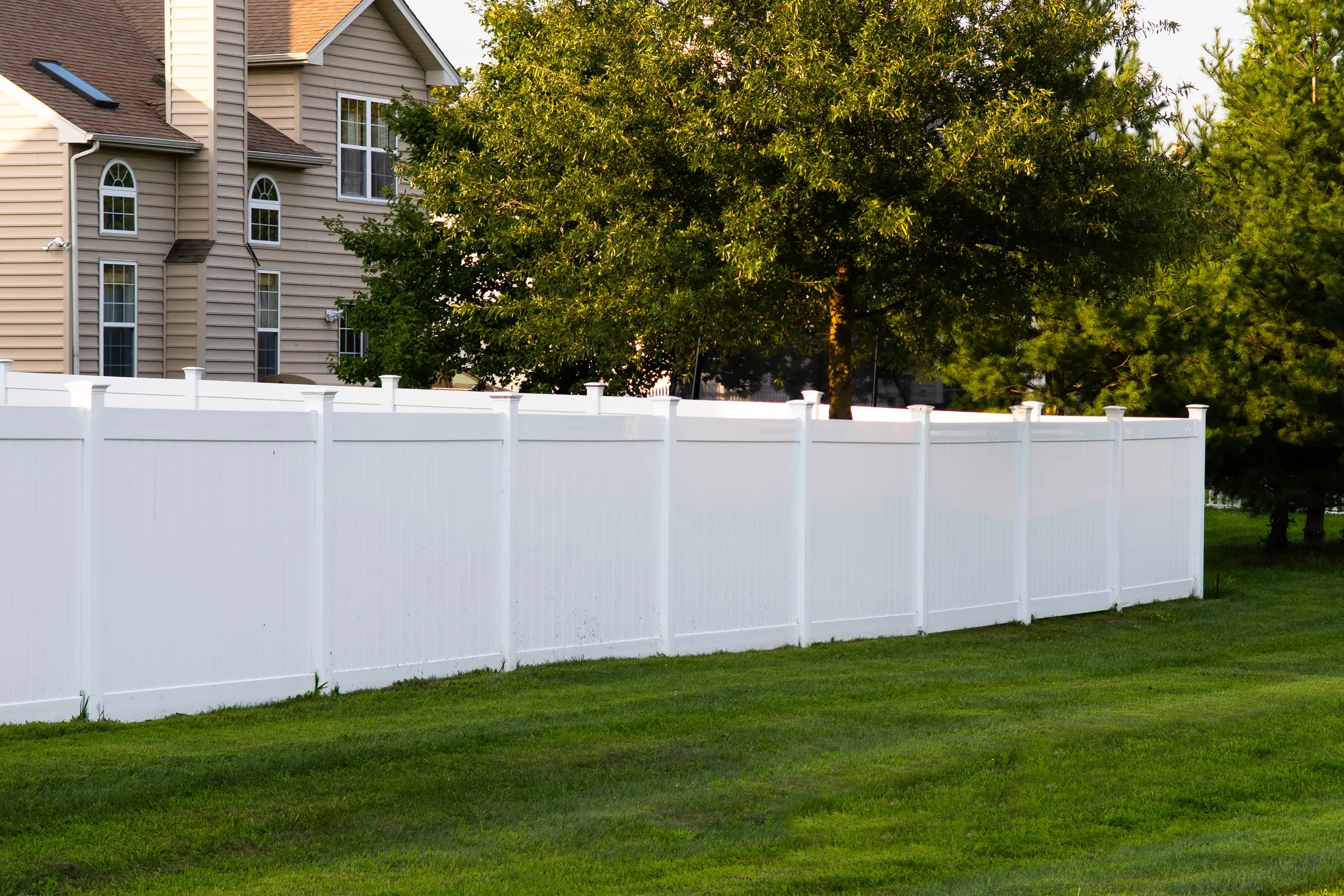 White vinyl privacy fence installed along a backyard property line